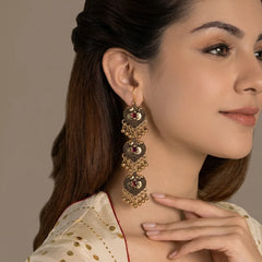 "Pair of antique gold-tone
 statement earrings featuring intricate floral detailing, deep red centre accents, layered circular drops, delicate chain links, and tiny dangling golden beads."
