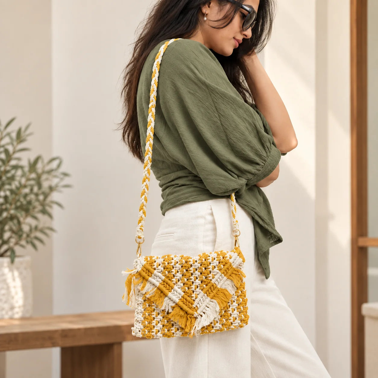 "Mustard and white
macramé bag featuring an intricate woven pattern, layered fringe detailing, and a braided shoulder strap."
