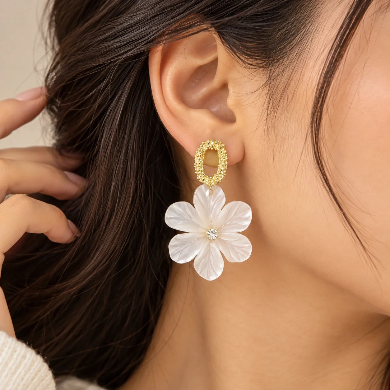 "White translucent floral
 drop earrings with layered flower petals and textured gold-toned oval stud tops, displayed on a white jewellery card."
