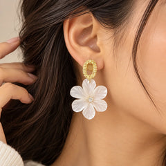 "White translucent floral
 drop earrings with layered flower petals and textured gold-toned oval stud tops, displayed on a white jewellery card."
