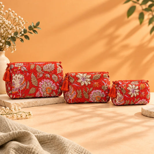 "Orangish Red pouch bag
 featuring intricate floral and botanical prints in cream, pink, orange and green, with decorative tassel accents."
