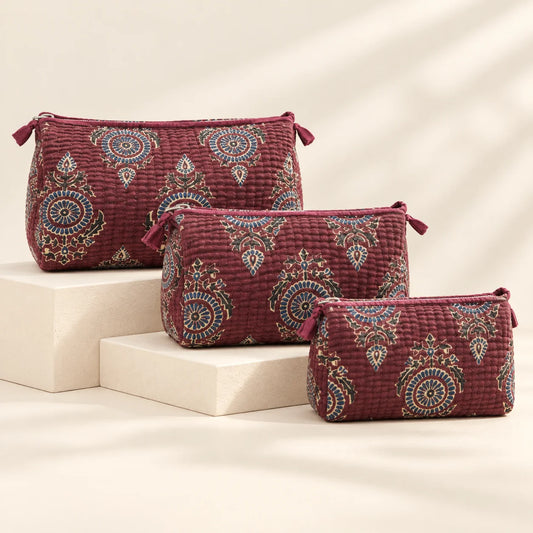 "Set of three maroon quilted
 fabric pouches featuring intricate traditional floral and ornamental motifs in beige, navy, and brown, arranged in different sizes."
