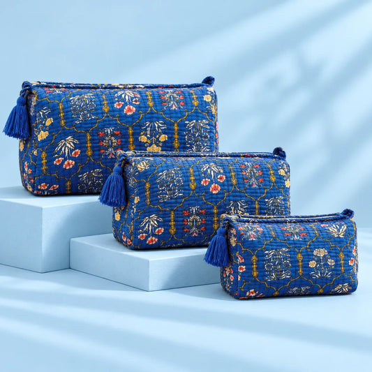 "Set of three royal blue
 quilted fabric pouches featuring intricate floral and ornamental prints with tassel details and arranged in different sizes."
