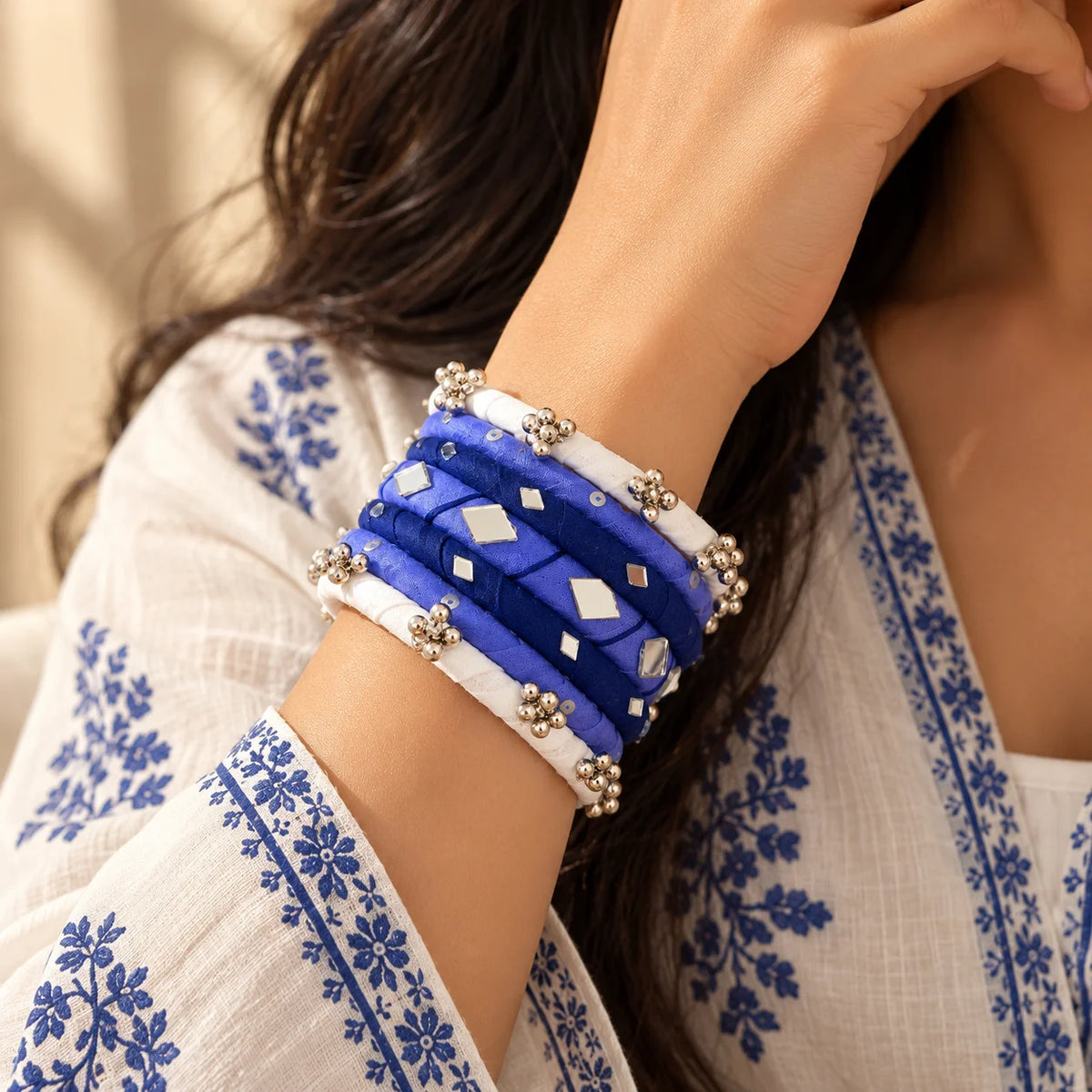 Lavender and white fabric-wrapped bangle set featuring silver-tone bead clusters, geometric mirror accents, and decorative dotted details, worn on the wrist.

