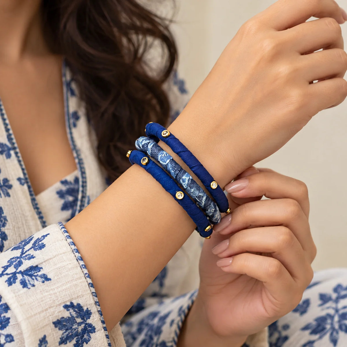 "Indigo fabric-wrapped 
bangle set featuring golden stones . "
