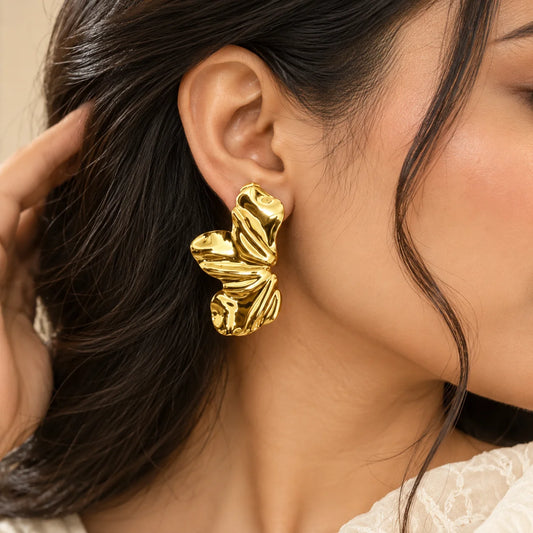 Gold sculpted leaf drop earrings featuring a wavy, textured design and a polished metallic finish.
