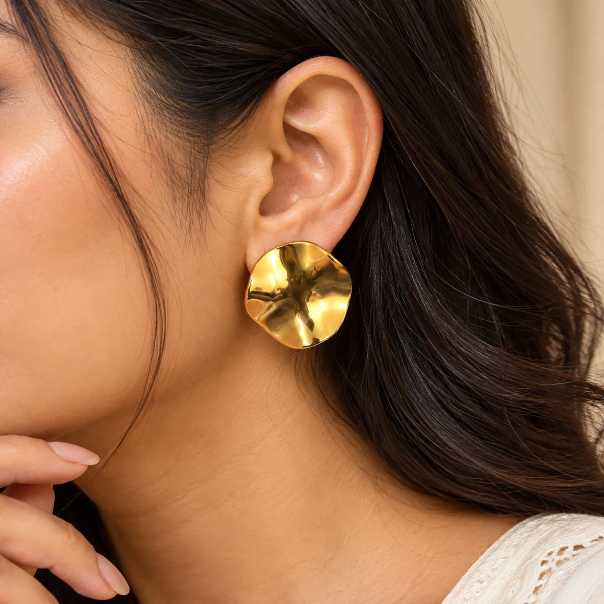 Gold sculpted disc earrings featuring an abstract wavy design and a high-shine polished finish.
