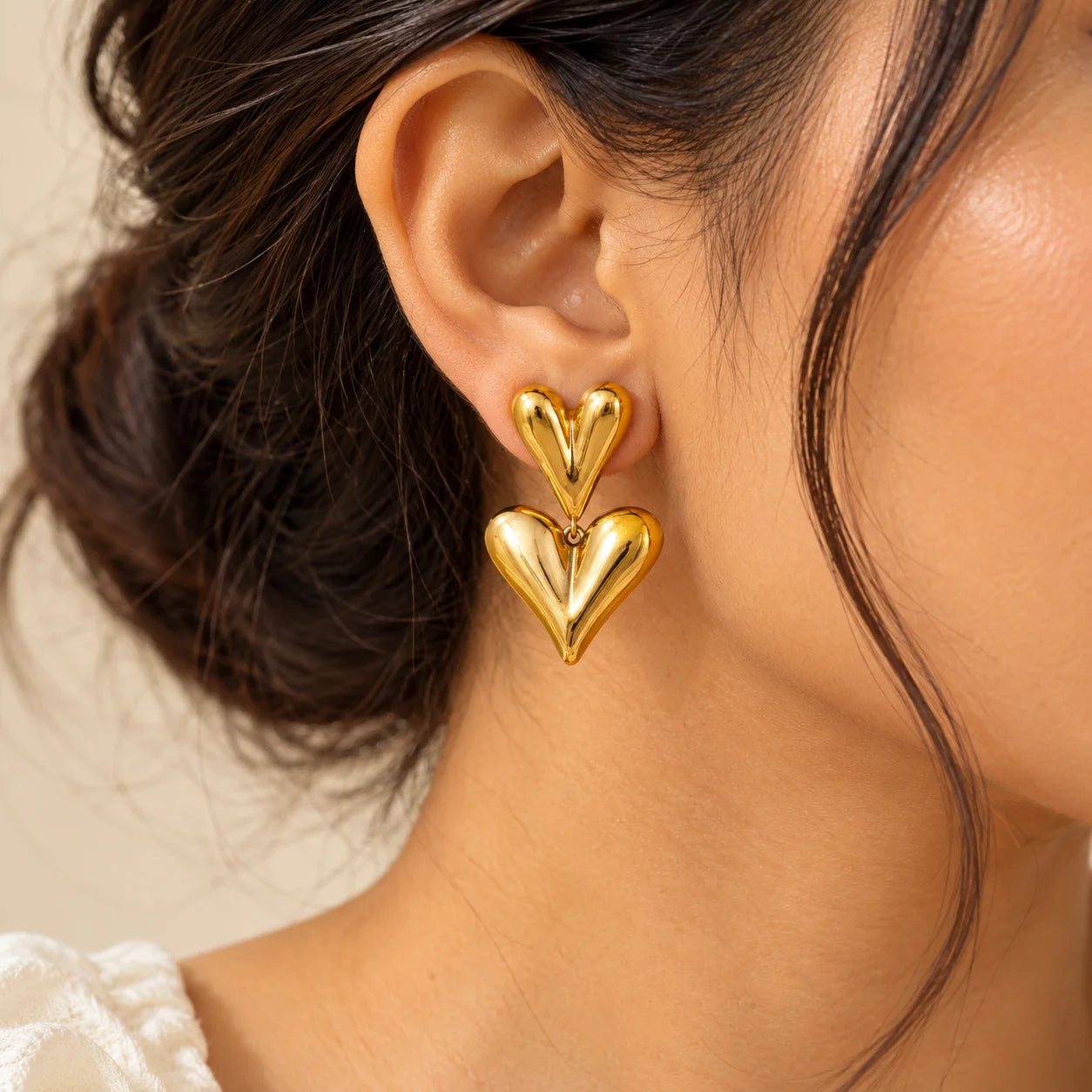 Gold double heart drop earrings featuring two sculpted heart shapes with a glossy polished finish.

