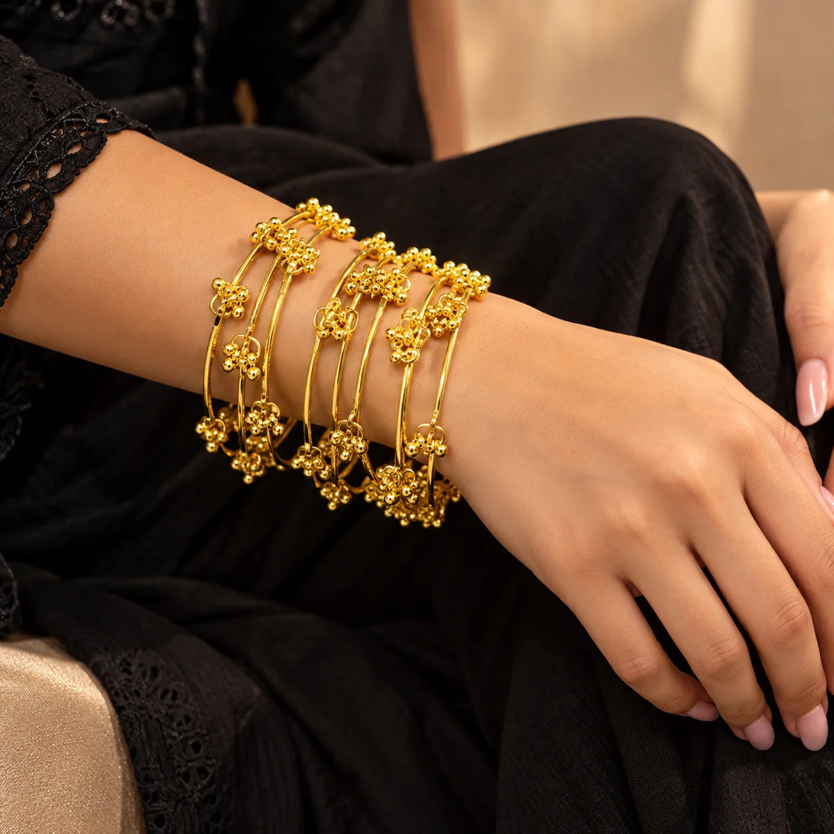 Gold-tone Kashmiri Jhumar bangles featuring slim bands, intricate floral clusters, and delicate dangling gold charms.

