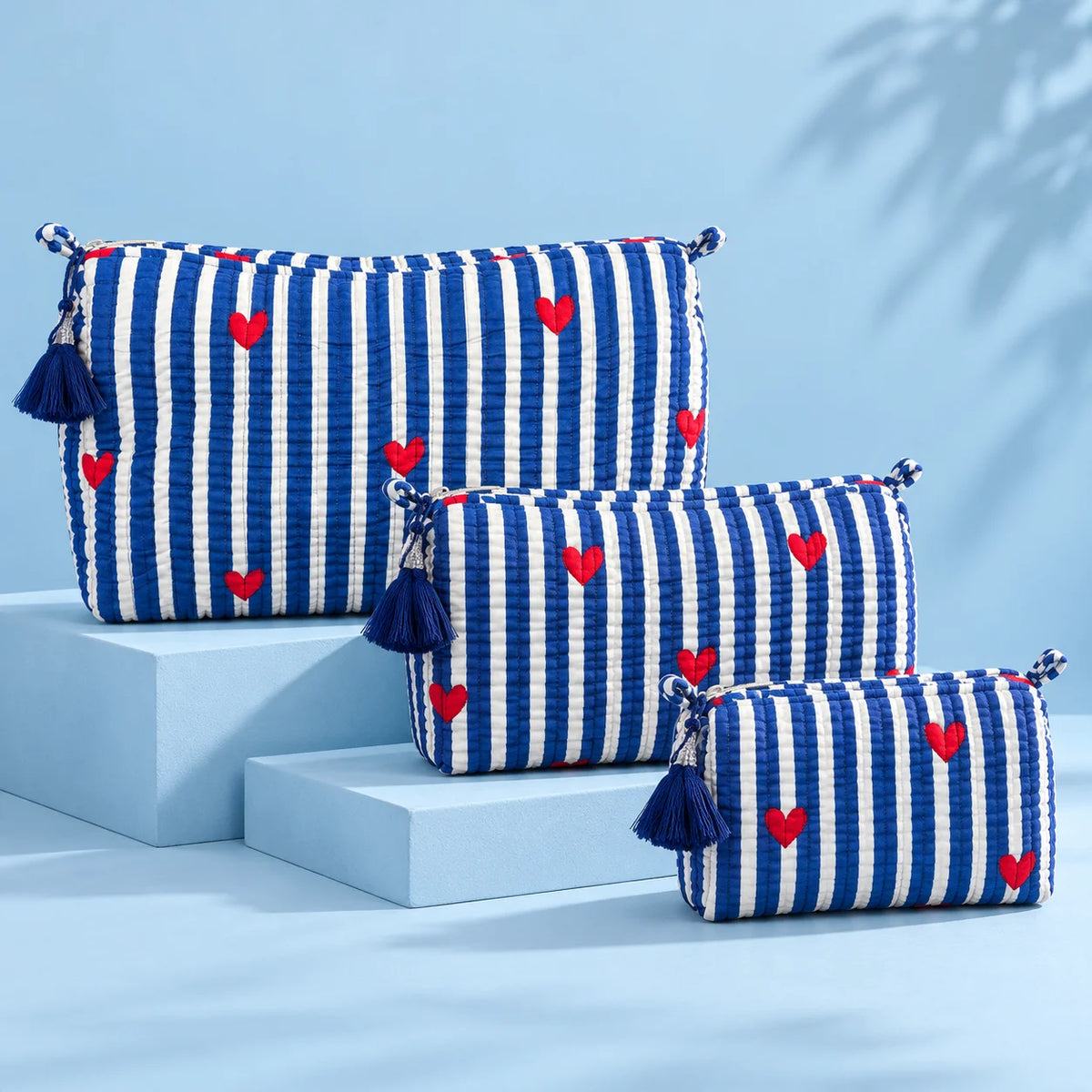 Blue and white striped pouch featuring red heart prints, a blue tassel, and a zip closure.
