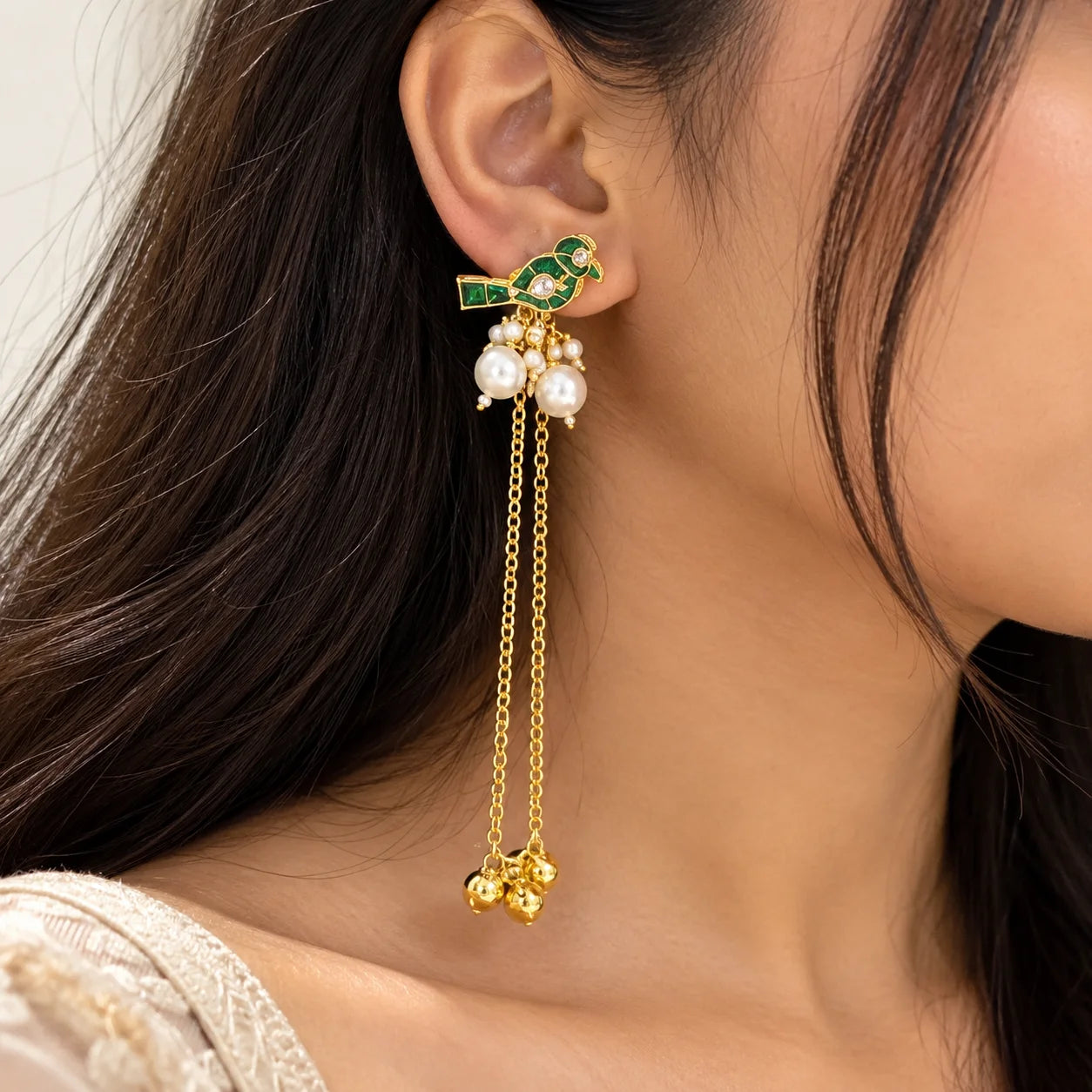 Green Kashmiri long earrings featuring bird motifs with green enamel detailing, pearl clusters, and dangling gold-tone chains with decorative charms.
