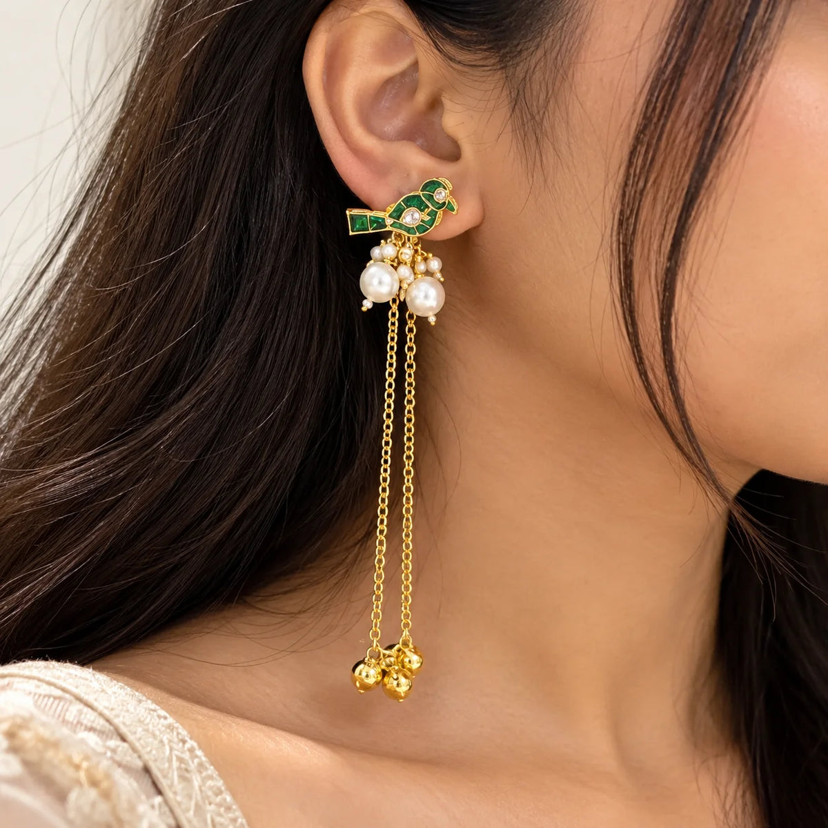 Green Kashmiri long earrings featuring bird motifs with green enamel detailing, pearl clusters, and dangling gold-tone chains with decorative charms.
