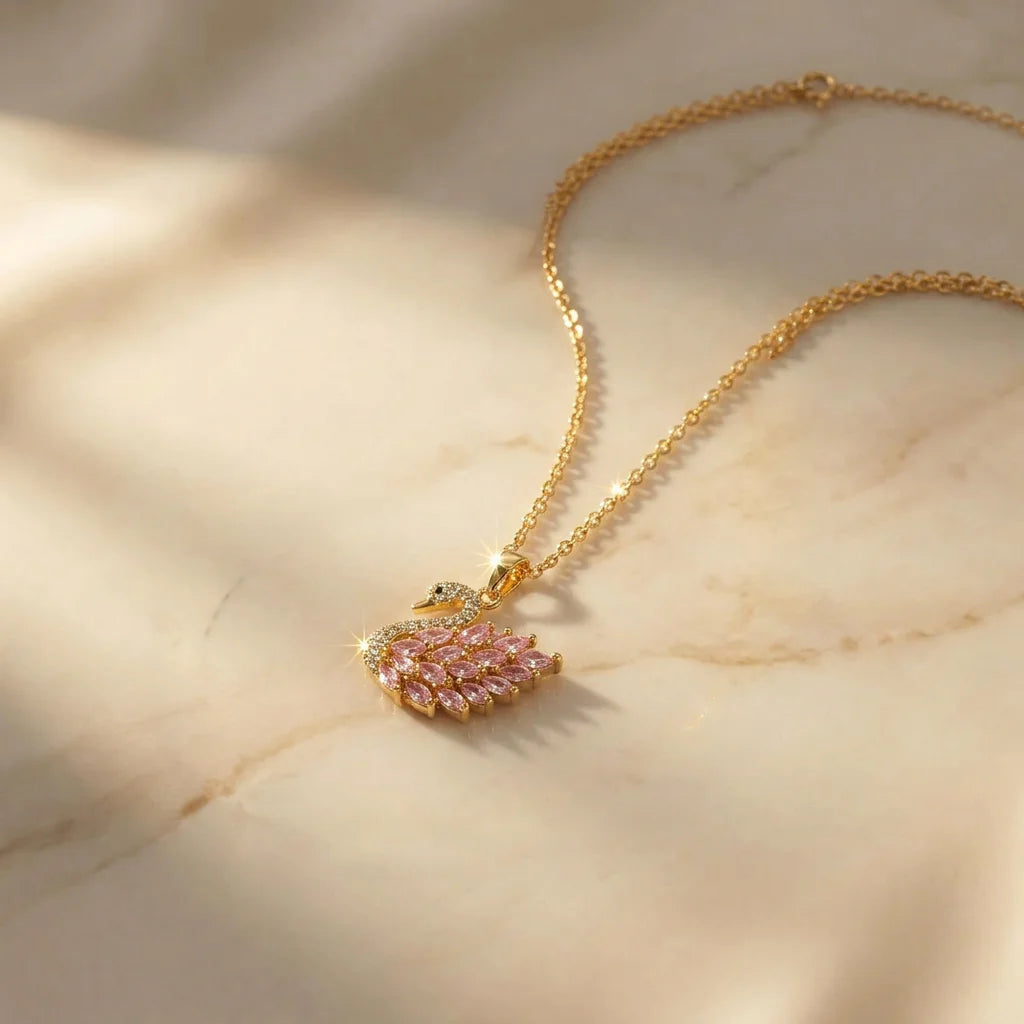 18K gold plated swan pendant necklace with clear cubic zirconia on the neck and pink marquise crystal feathers. The delicate gold chain highlights the elegant swan design. Perfect feminine demi-fine jewelry for daily wear or gifting.
