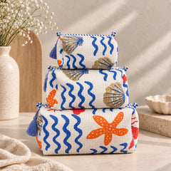 "Set of three quilted 
fabric pouch bags featuring blue wave patterns with orange,  and gold accents, finished with decorative tassels and displayed stacked together."
