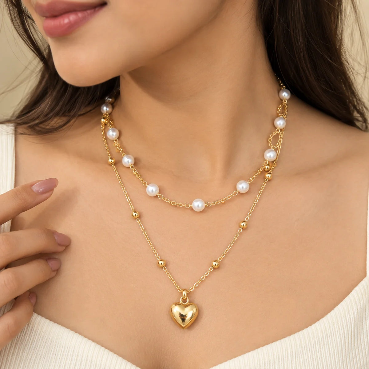 "Delicate layered necklace
 featuring pearl-like beads, gold-toned accents, fine chain detailing, and a small heart-shaped pendant."

