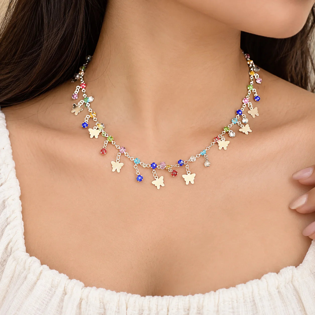 "Silver-toned charm
 necklace featuring multiple white butterfly charms and colourful faceted beads in pink, blue, purple, red, and yellow."
