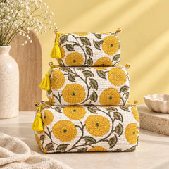 "Set of quilted pouches
 featuring a white base with yellow floral and green leaf prints, finished with decorative yellow tassels."
