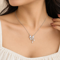 "Silver-toned necklace
 featuring a delicate bow-shaped pendant with sparkling crystal details and small dangling charms on a fine chain."

