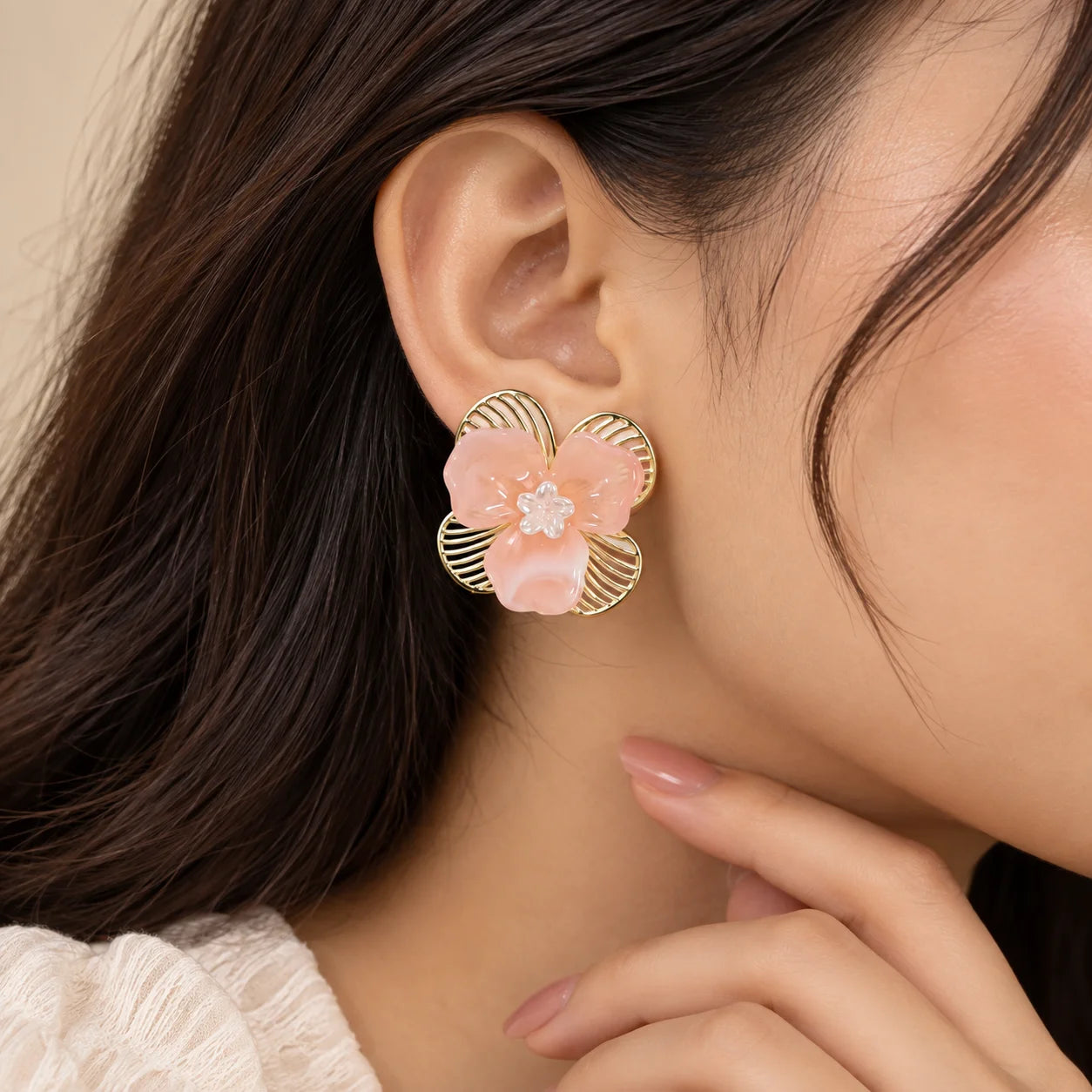 "Pair of floral earrings
 featuring peach flower petals, gold-toned leaf detailing, and delicate translucent flower accents at the centre."
