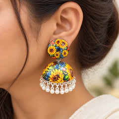 "Colorful floral jhumka
 earrings featuring vibrant yellow sunflowers, multicolored flowers, and green foliage on a dark background, finished with white bead danglers."
