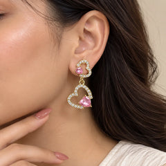 "Pair of elegant
 earrings featuring double heart-shaped designs, sparkling crystal-studded outlines, and pink heart-shaped stones."
