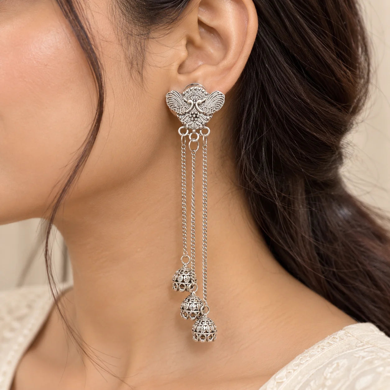 "Pair of antique silver
-toned earrings featuring intricate peacock-inspired motifs with multiple long cascading chain drops, shown against a light background."
