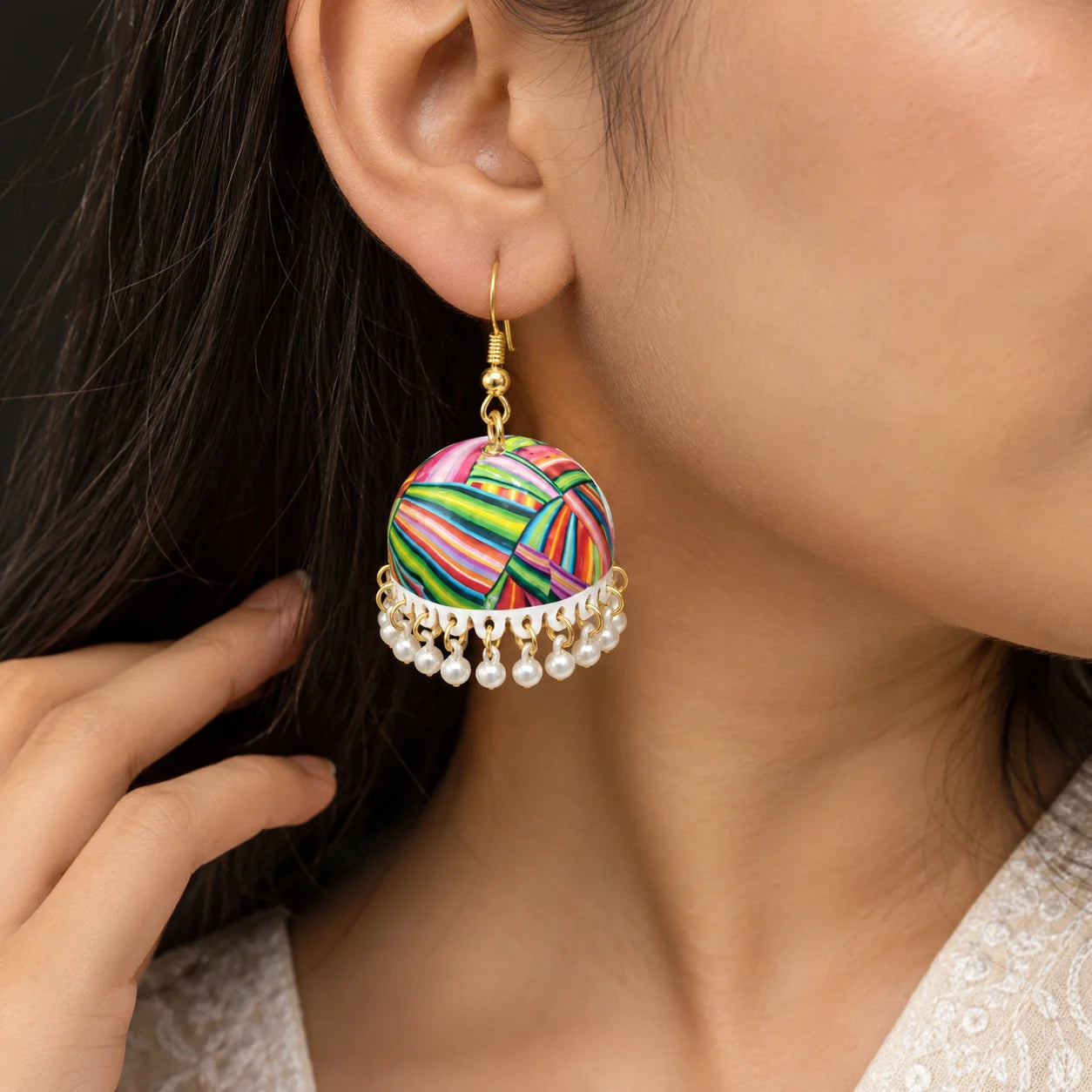 "Pair of colourful jhumka
 earrings with vibrant pink, green, yellow, blue, orange, and purple striped patterns, finished with delicate white bead danglers and gold-tone hooks."
