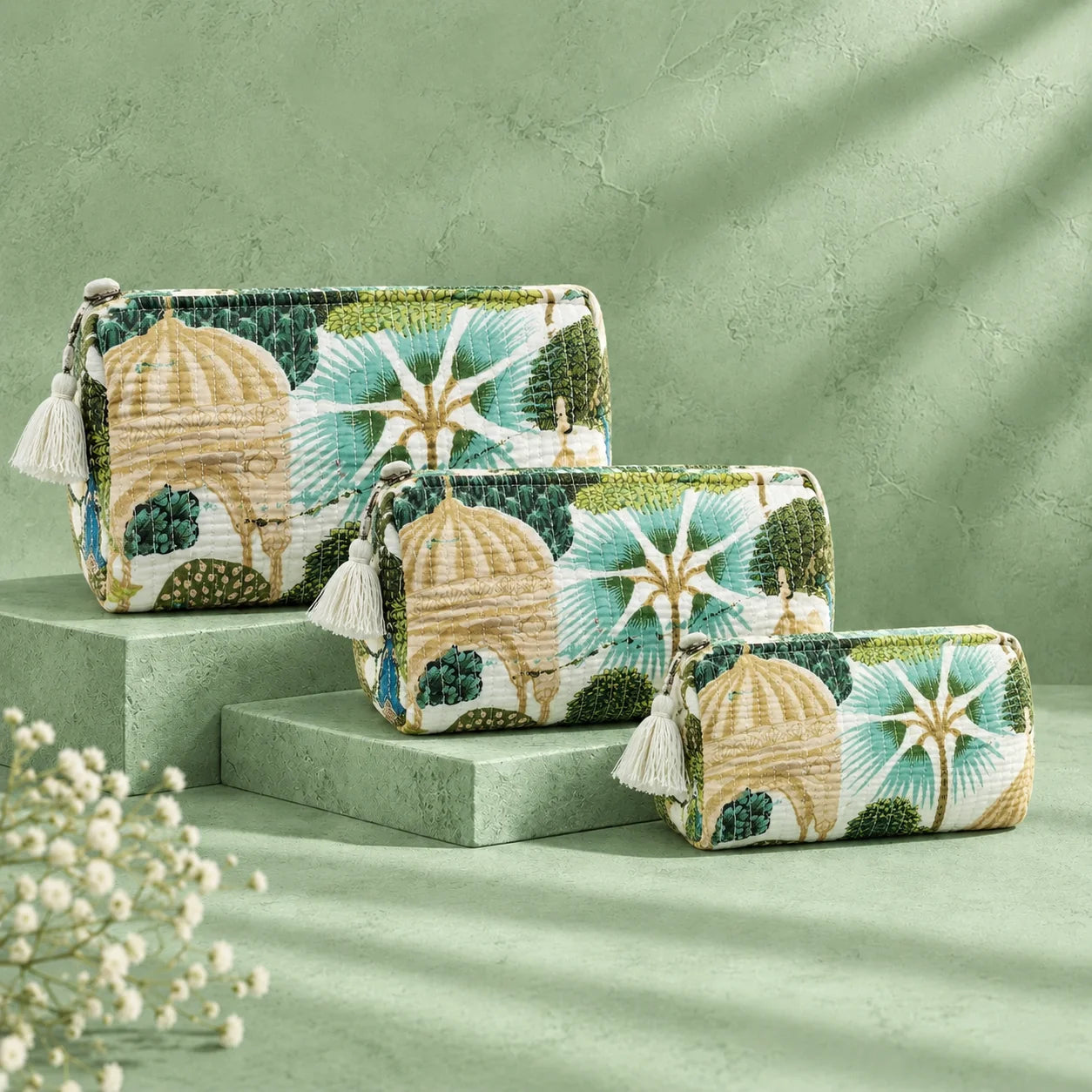 "Set of quilted fabric
 pouches in green, cream, and beige, featuring botanical foliage, leafy patterns, and colorful peacock motifs."

