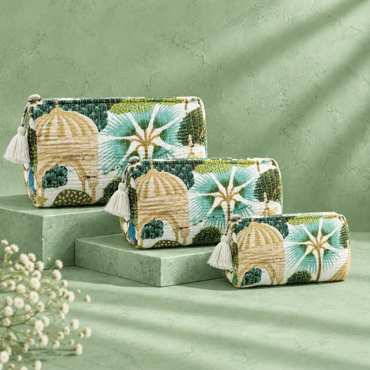 "Set of quilted fabric
 pouches in green, cream, and beige, featuring botanical foliage, leafy patterns, and colorful peacock motifs."
