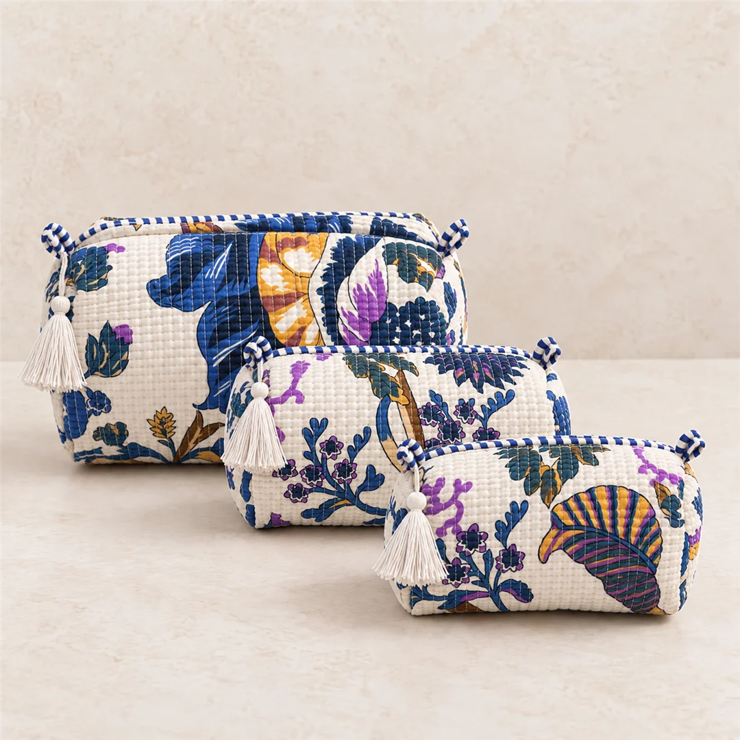 "Set of three quilted fabric
 pouch bags with vibrant blue, purple, mustard, and green floral botanical prints, stacked together on a wooden surface."
