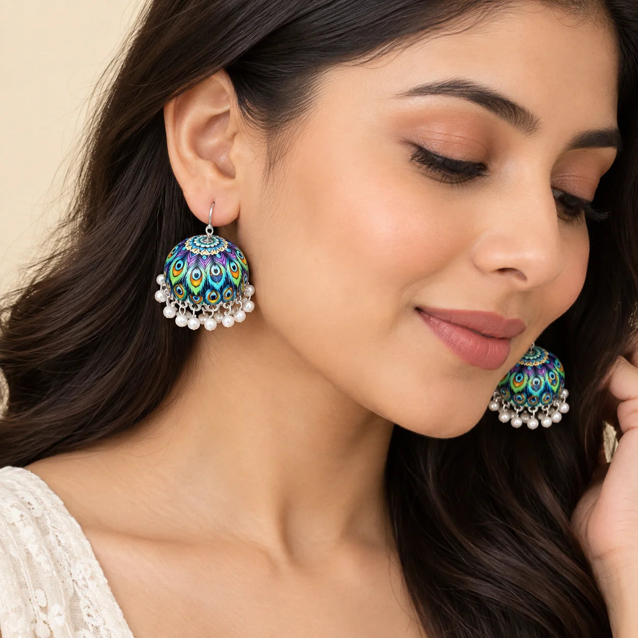 "Pair of colorful peacock-inspired
 jhumka earrings with purple, blue, green, and turquoise feather-patterned domes, finished with delicate white bead danglers."
