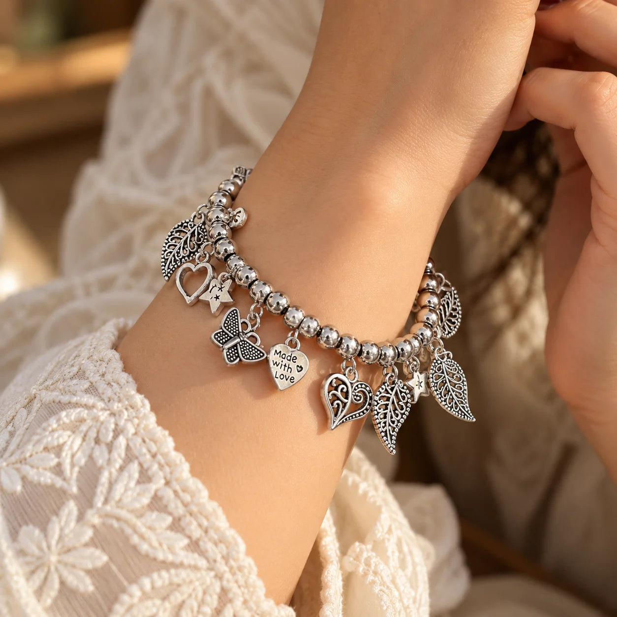 "Silver-toned beaded
 charm bracelet featuring intricate paisley, heart, butterfly, and star-shaped charms arranged around the bracelet."
