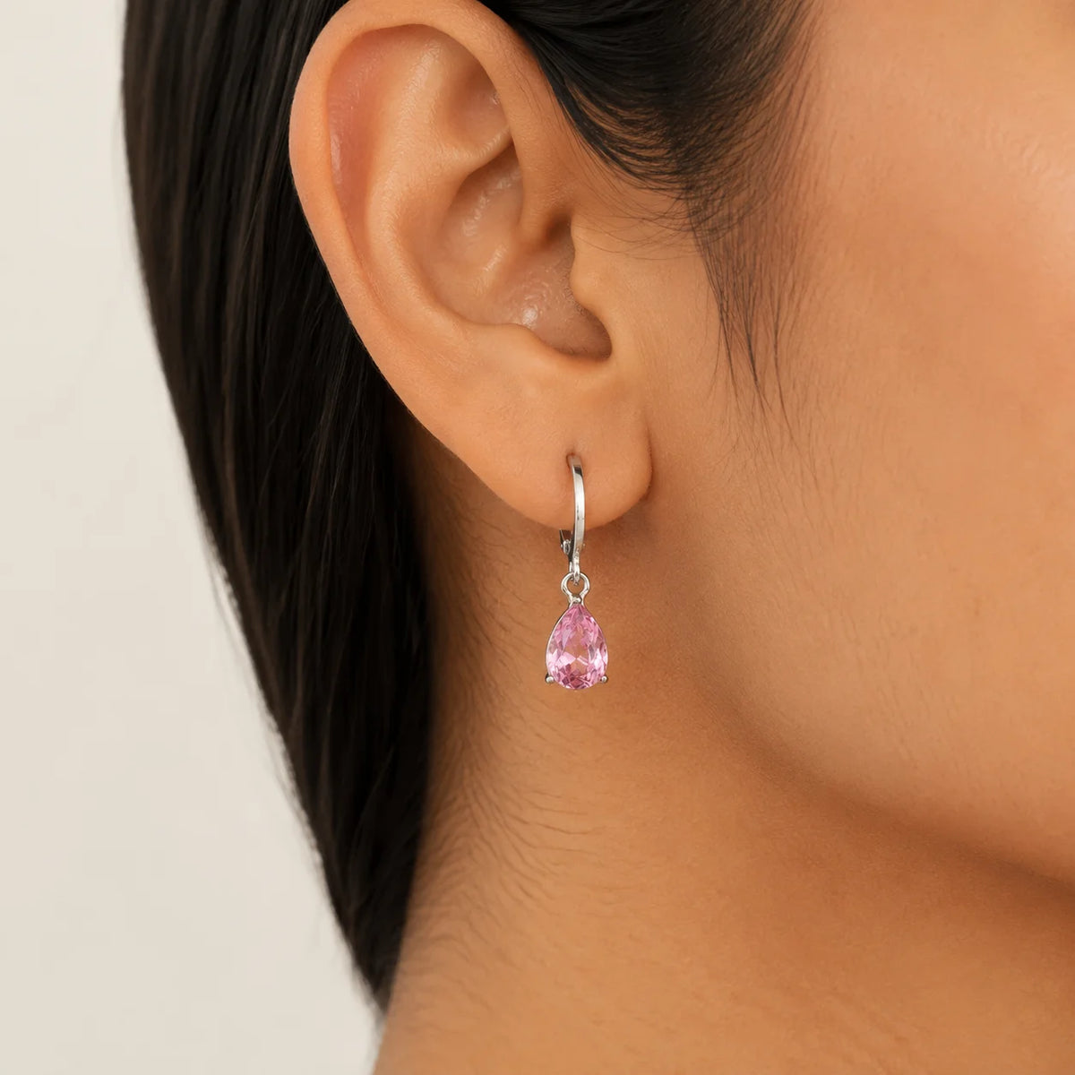 Silver tone pink crystal drop huggie earrings with teardrop stone
