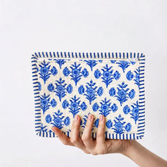 "Blue and white quilted
 fabric pouch featuring a repeating floral print and striped border detailing."
