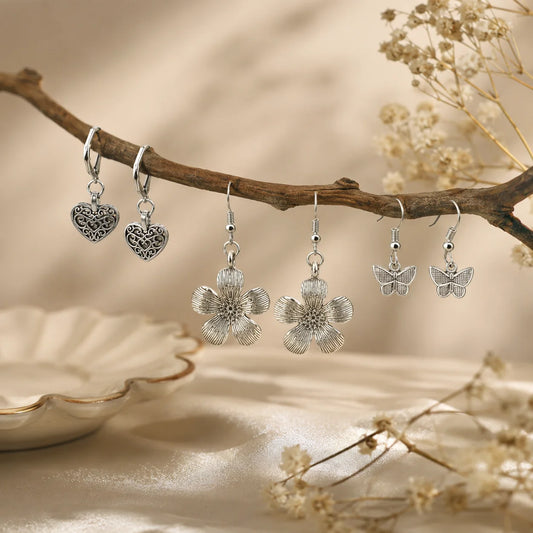Set of 3 oxidised silver earring pairs. Butterfly hook earrings, filigree heart lever-back earrings, and large flower hook earrings. Antique silver feminine combo.
