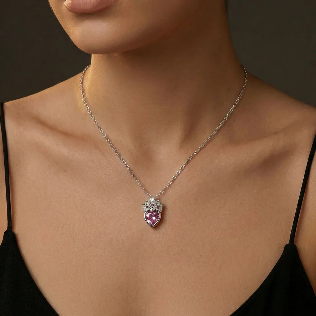 Stainless steel pendant necklace featuring a faceted pink heart crystal with clear and pink accent stones in a crown design. The hypoallergenic silver tone chain is tarnish-resistant and lightweight. Perfect coquette style necklace for parties and casual outfits.
