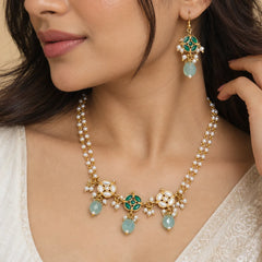 Sea green kundan pearl necklace set with layered white pearl strands, green and white floral detailing, sea green bead drops, and matching earrings.

