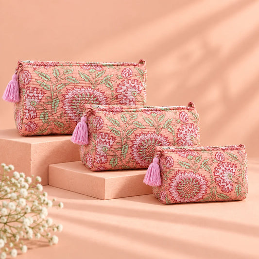 "Set of three peach
 fabric pouches featuring intricate floral and leafy prints in burgundy, rose, and green, arranged in different sizes."
