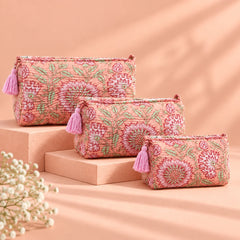 "Set of three peach
 fabric pouches featuring intricate floral and leafy prints in burgundy, rose, and green, arranged in different sizes."

