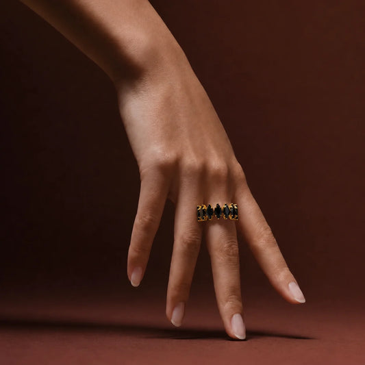 Gold open cuff ring with black marquise crystals on wooden table. Adjustable gold-tone ring featuring black stones and ball-end detailing.
