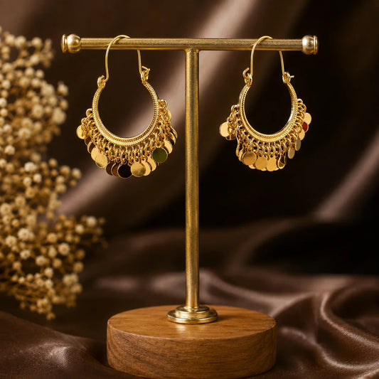 These gold tone bali earrings feature a wide U-hoop frame lined with multiple rows of hanging coin discs. Every step creates movement and   sound of festive jewellery. High-shine gold plating with detailed wire work on the hoop. Wire hook closure makes them easy to wear. Large look but surprisingly lightweight because the discs are hollow.
