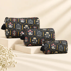 "Set of Black fabric pouches
 with intricate floral and botanical prints in white, beige, red, and mustard yellow, featuring decorative black tassel accents."
