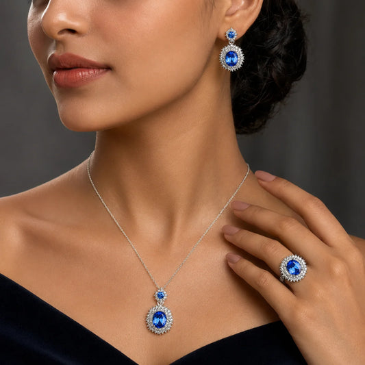 "Silver-tone jewellery set
 featuring a royal blue crystal pendant necklace with matching blue crystal stud earrings, accented with sparkling halo stones for an elegant look, perfect for parties, weddings, gifting, and special occasions."
