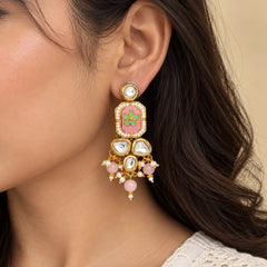 "Gold-toned statement
 earrings featuring pink enamel panels with green floral motifs, clear Kundan-style stones, white pearl detailing, and cascading blush-pink beads."
