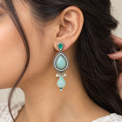 Silver-toned statement earrings with large mint green teardrop stones, green accents, sparkling clear stone detailing, and cascading white pearl embellishments.

