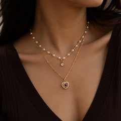 "Gold-tone layered pearl necklace featuring delicate 
faux pearls, a vintage-inspired heart pendant with
 pearl detailing, and a dainty crystal charm. Elegant
 women's fashion jewellery for everyday wear, 
parties, and special occasions."
