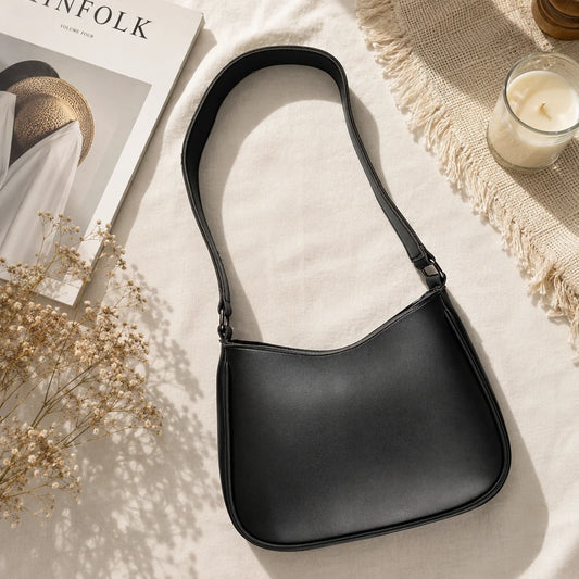 "Elegant black vegan leather 
shoulder bag featuring a sleek curved silhouette, smooth premium finish, spacious interior, and a timeless minimalist design, making it the perfect everyday handbag for work, shopping, travel, brunch, and casual outings."
