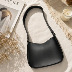 "Elegant black vegan leather 
shoulder bag featuring a sleek curved silhouette, smooth premium finish, spacious interior, and a timeless minimalist design, making it the perfect everyday handbag for work, shopping, travel, brunch, and casual outings."
