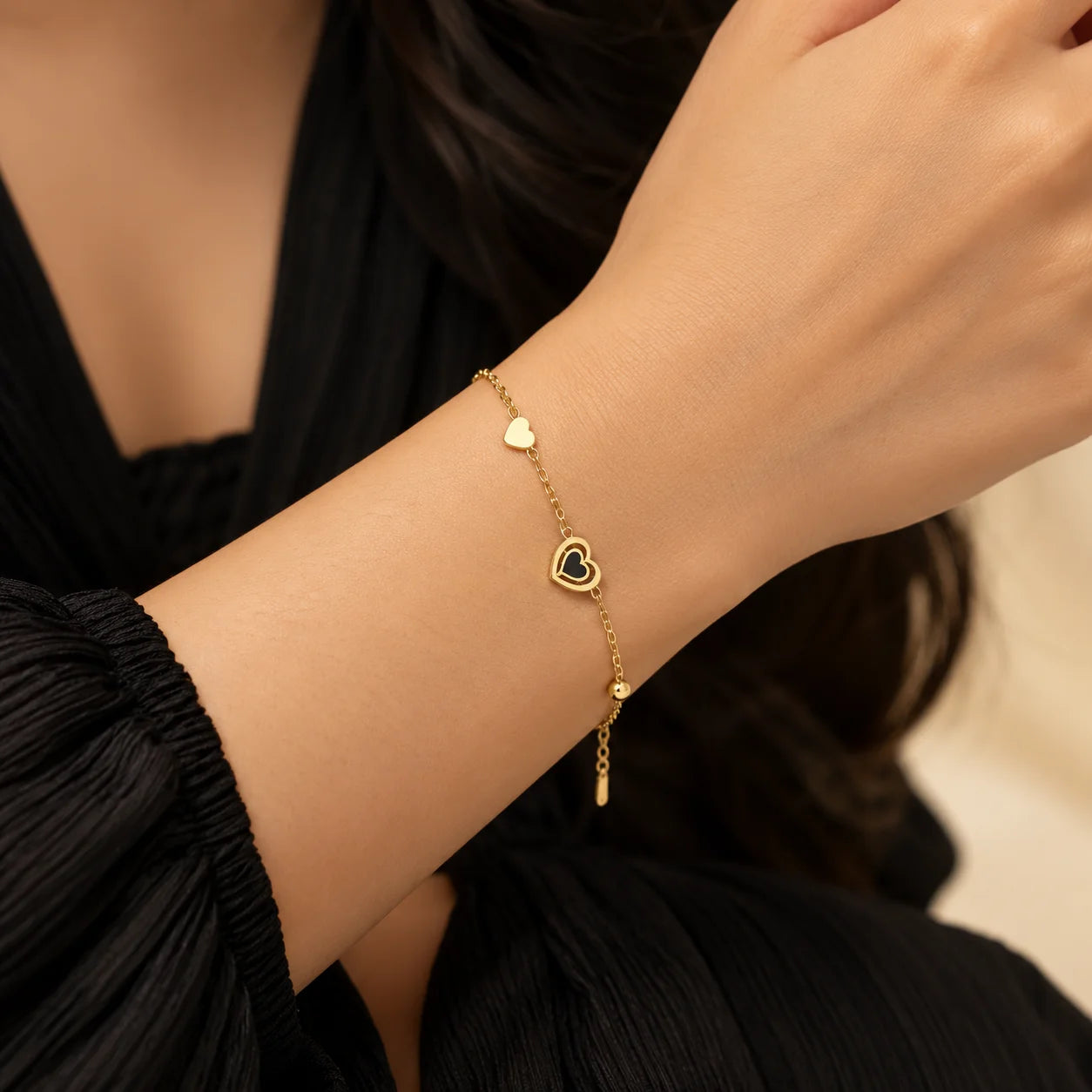 "Gold-toned link bracelet
 featuring two heart charms, including a solid heart and an open heart design, with an adjustable chain closure."
