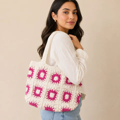 "White crochet shoulder 
bag featuring pink and magenta floral motifs, a textured patchwork design, and long crochet handles."
